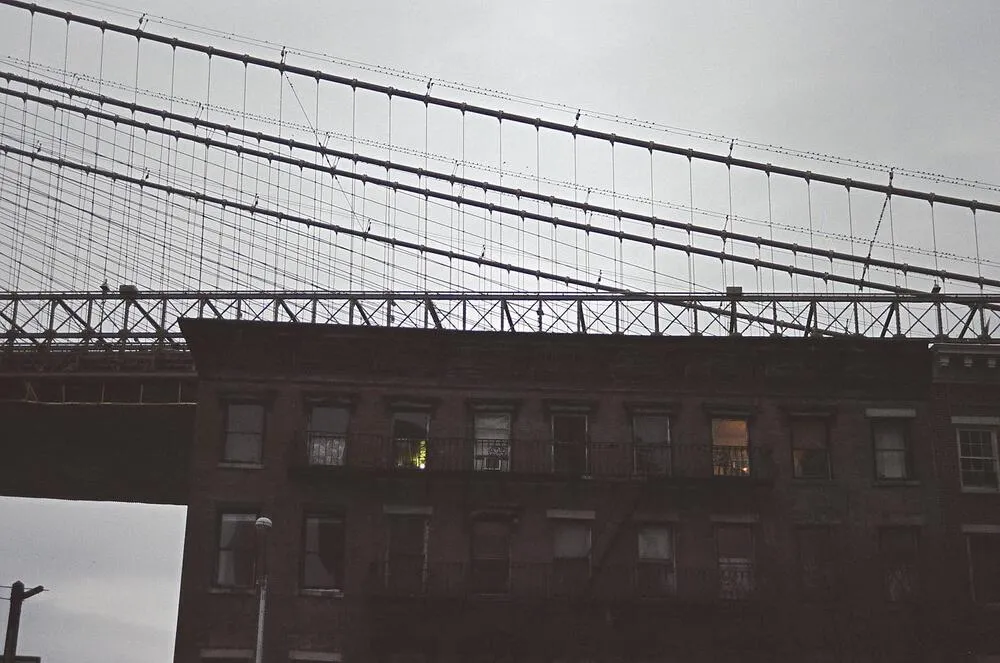 Suspension bridge above brick buildings in New York