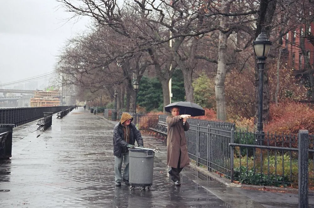 People walking along a rainy riverside promenade in New York